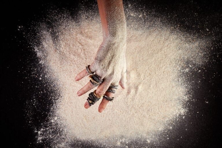 Foto de mão feminina com joias sobre farinha de mandioca