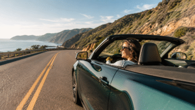 Mulher dirigindo carro conversível em uma estrada