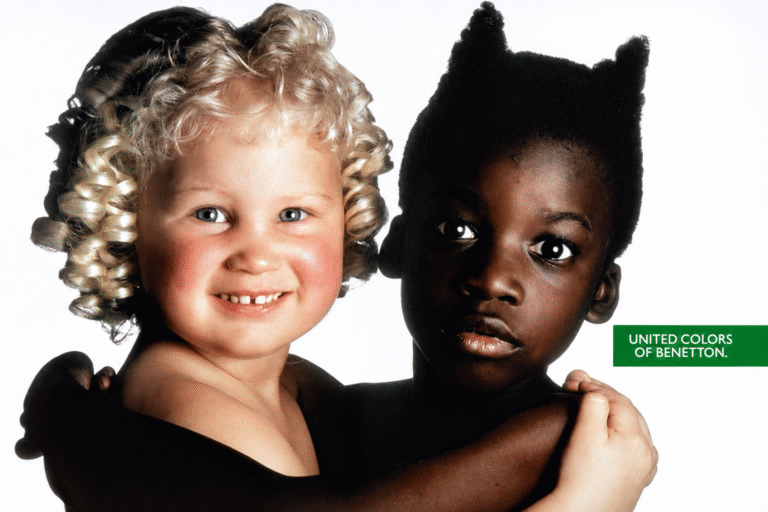Duas crianças aparecem abraçadas em um anúncio da Benetton de 1991: uma menina branca, loira e de cachos claros, e uma criança negra com o cabelo estilizado em pontas, em composição que ficou conhecida como Angel & Devil.