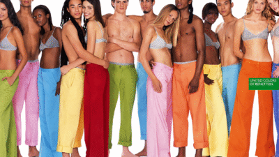 Grupo diverso de jovens posa diante de fundo branco em campanha da Benetton de 2002, usando roupas coloridas