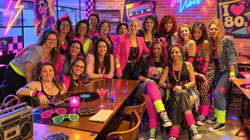 Grupo de mulheres em releitura inspirada nos anos 80, com roupas neon, ombreiras, polainas e cabelos volumosos