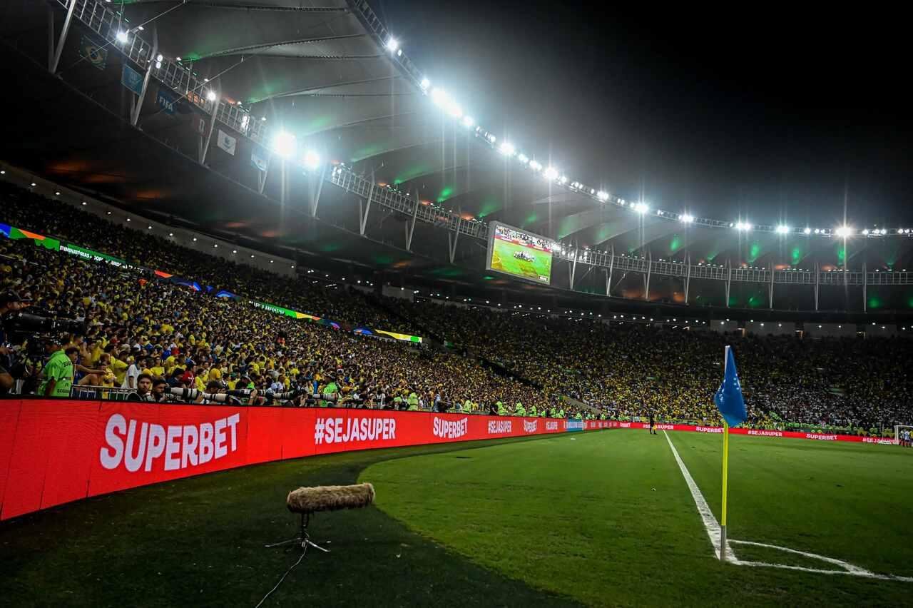 Campo de futebol à noite com placas de publicidade ao redor do gramado